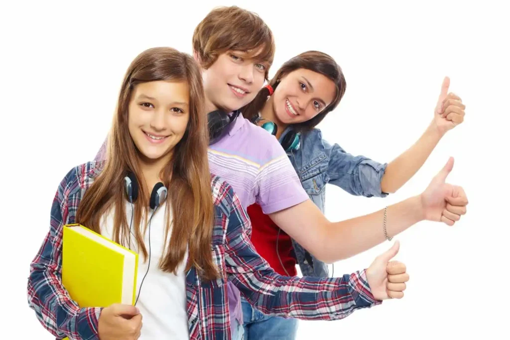 Group of smiling students holding books and showing thumbs up isolated on white background
